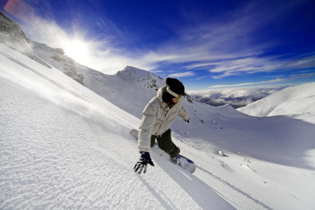man snowboarding, touching the snow